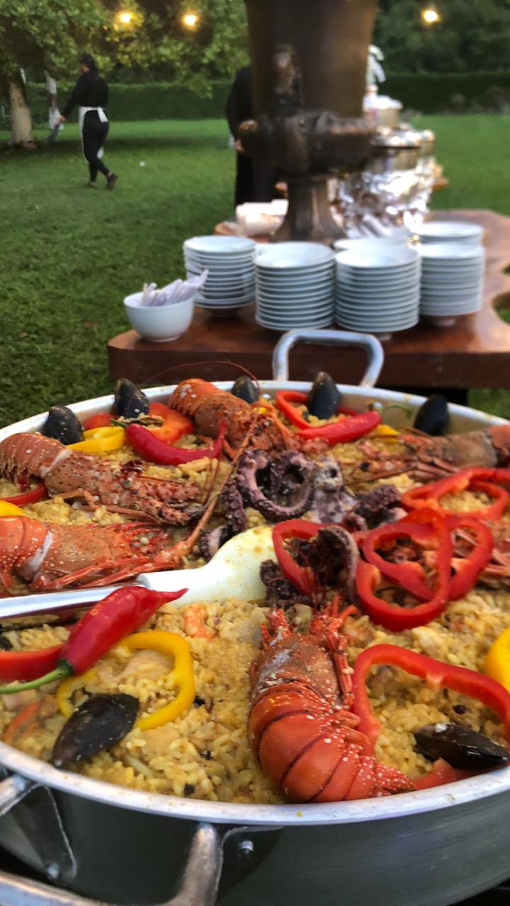 grande paella de frutos do mar com lagostas, polvo, mexilhões e pimentões num bufê ao ar livre em um jardim